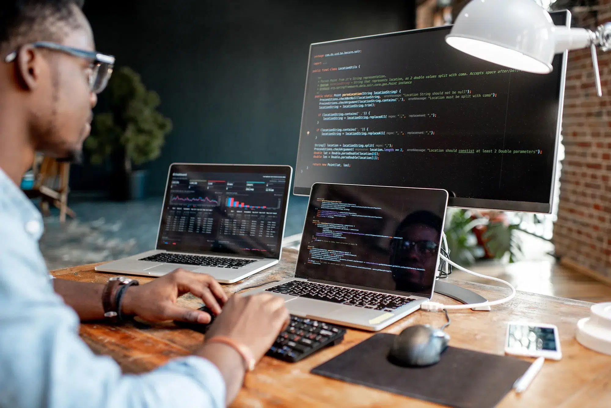 Image of man sitting in front of two laptops