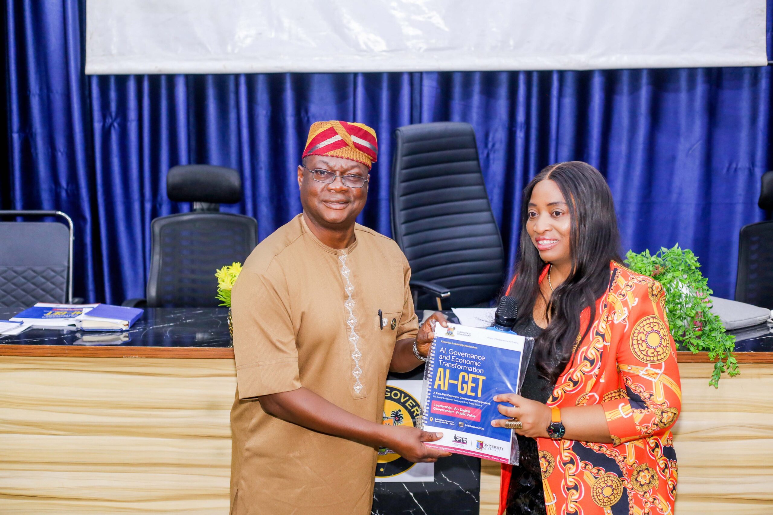 Professor Ogechi Adeola presenting the AI-GET handbook to Mr Adedolapo Sulaimon Ajayi of the Lagos State Ministry of Establishments and Training.